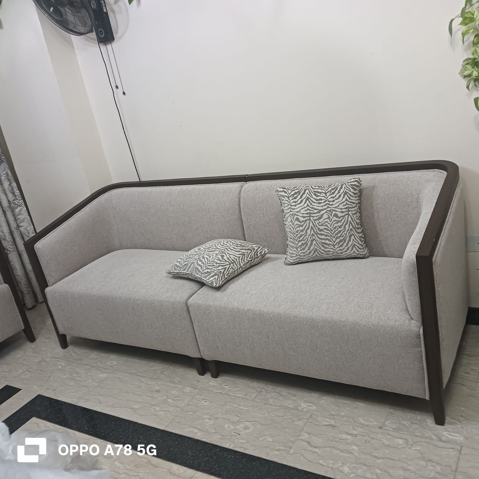 Custom grey fabric sofa with dark wood trim by Dune Home Dubai